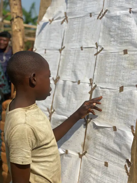 Enfant près d’un tableau — Basankusu · 2022